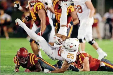  ?? [AP PHOTO] ?? Texas running back Chris Warren III is upended by Iowa State defenders during Thursday night’s Big 12 football game in Ames, Iowa. Texas took on Iowa State on Thursday night in a Big 12 football game in Ames, Iowa..