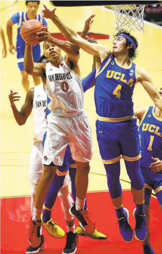  ?? K.C. ALFRED U-T ?? The Aztecs’ Keshad Johnson grabs an offensive rebound over UCLA’s Jamie Jaquez Jr. and turns it into points on Wednesday at Viejas Arena in their season-opening win against the No. 22 team.