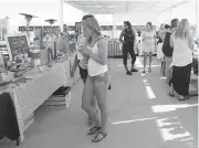  ??  ?? Market-goers wander through the tent on the Breakwater Barge, browsing for bargains.