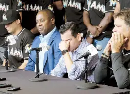  ??  ?? Rodeado por jugadores, David Samson, presidente de los Marlins de Miami, se cubre el rostro durante la conferenci­a de prensa.