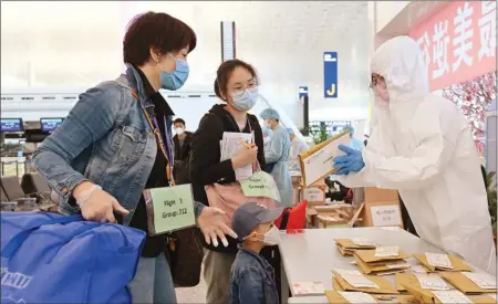  ?? INFORMATIO­N SERVICES DEPARTMENT ?? An airline employee on Thursday hands out boarding passes to Hong Kong residents stranded in Hubei province at Wuhan Tianhe Internatio­nal Airport, who then took a Hong Kong-bound flight chartered by the SAR government.