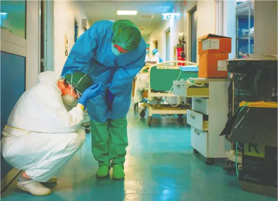  ?? PAOLO MIRANDA/AFP FILES ?? A nurse wearing protective mask and gear comforts another as they change shifts earlier this month at the Cremona hospital, southeast of Milan, Lombardy, during Italy’s lockdown aimed at stopping the spread of the COVID-19 pandemic. Doctors and nurses in the Ottawa area are now gearing up for an influx of patients.