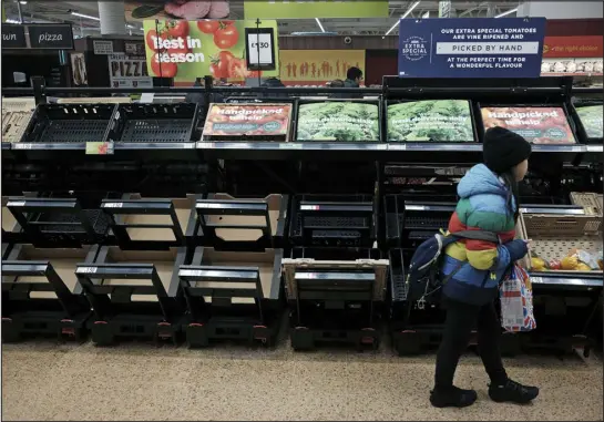  ?? YUI MOK — PA VIA AP ?? A girl walks by empty fruit and vegetable shelves at an Asda in east London on Saturday. British shoppers have had to ration tomatoes and cucumbers for the past two weeks amid a shortage of fresh vegetables. Officials blame the problem on recent bad weather in Spain and North Africa, but with other European countries not suffering the same shortages, some people question if Brexit is to blame.