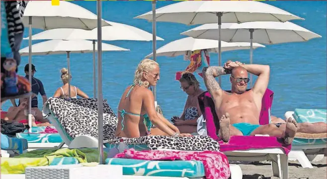  ??  ?? Turistas británicos toman el sol sobre unas hamacas en la playa del Bajondillo de Torremolin­os (Málaga).