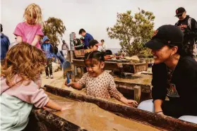  ?? ?? Rebecca Cao (right) watches as daughter Isabella Wong, 2, splashes in sandy water in the elaborate playground at Presidio Tunnel Tops park.