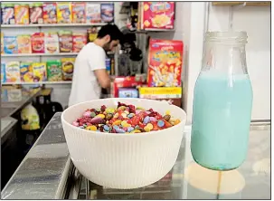  ?? AP/ALBERT STUMM ?? A bowl of sugary cereals, topped with candy, is displayed at El Flako in Barcelona, Spain, as one of the cafe owners, Nicolas Castan, prepares a more healthful combinatio­n.