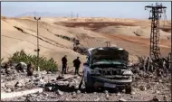  ?? (AP/Baderkhan Ahmad) ?? People inspect a site damaged by Turkish airstrikes that hit an electricit­y station Sunday in the village of Taql Baql, in Hasakeh province, Syria.