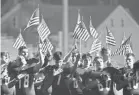  ??  ?? The Mount Carmel Area High School team holds U.S. flags as the national anthem is played before a football game in Mount Carmel, Pa.
LARRY DEKLINSKI/AP