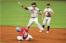  ?? Eric Espada / Getty Images ?? Giants shortstop Brandon Crawford maneuvers around the slide by Miami’s Garrett Cooper to make a throw to complete a double play Saturday.