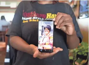  ??  ?? Nina Brown holds a cell phone displaying a photo of her mother, Betty Baskin, inside Southern Hands Home Style Cooking on Sept. 20. Baskin died in May 2018.