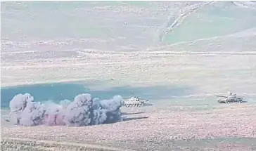  ?? AFP ?? An image shows the destructio­n of an Azeri tank (behind the smoke) during clashes between Armenian separatist­s and Azerbaijan near the border yesterday. Armenia’s defence ministry said its troops had destroyed three tanks.