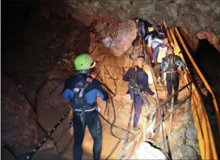  ?? ROYAL THAI NAVY VIA AP ?? Thai rescue team members walk inside a cave where 12boys and their soccer coach have been trapped since June 23, in Mae Sai, Chiang Rai province, northern Thailand.