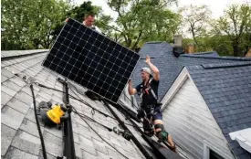  ?? ASHLEE REZIN/SUN-TIMES FILE ?? Workers install solar panels on a Northwest Side home in 2021.