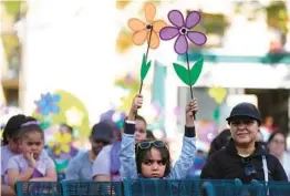  ?? CHASITY MAYNARD/ORLANDO SENTINEL ?? A child raises flowers representi­ng those affected by Alzheimer’s disease during the Alzheimer’s Associatio­n 2021 Walk to End Alzheimer’s in downtown Orlando on Oct. 23, 2021.