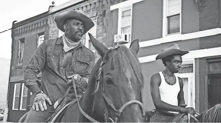  ?? NETFLIX ?? | 9B
Harp (left, Idris Elba) teaches his estranged son Cole (Caleb Mclaughlin) how to ride a horse in the Netflix film “Concrete Cowboy.”