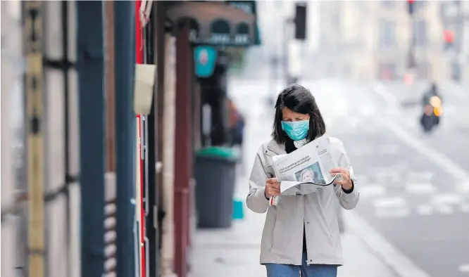  ?? CHRISTIAN HARTMANN/REUTERS ?? França. Mulher com máscara lê jornal em rua vazia: programas jornalísti­cos da TV, com 61%, e jornais impressos, 56%, lideram índices de confiança do público para se informar sobre pandemia