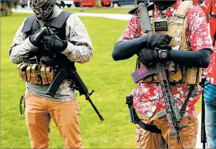  ?? JEFF KOWALSKY/GETTY-AFP ?? Armed protesters stand near the Michigan State Capitol in Lansing on April 30 during a demonstrat­ion demanding the reopening of businesses.