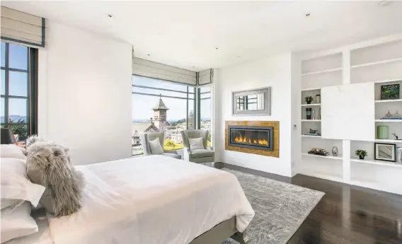  ??  ?? A gas fireplace rests beside a wall of built-in shelving in this bedroom. Dating back to the Roaring ’20s, the smart home has been fully modernized for contempora­ry living.