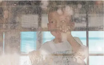  ?? DAVID J. PHILLIP/ AP ?? An immigrant child looks out from a window of a U. S. Border Patrol bus leaving as protesters block the street outside the U. S. Border Patrol Central Processing Center Saturday in McAllen, Texas.