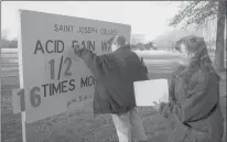  ?? HARTFORD COURANT 1997 ?? Chemistry students at St. Joseph College in January 1997 change a sign showing motorists how much acid rain has fallen in West Hartford. The Clean Air Act of 1990, championed by President George H.W. Bush, addressed the growing concern about acid rain.