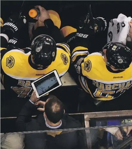  ?? STEVE BABINEAU/NHL VIA GETTY IMAGES ?? Assistant coach Jay Pandolfo of the Boston Bruins uses an iPad Pro to watch the play against the Ottawa Senators in playoff action last month.