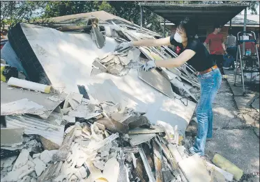  ?? AP/CHARLIE RIEDEL ?? Lucy Liu dumps trash on a pile of debris Thursday as she helps her co-worker Tianna Oliver clean out her flood-damaged house in Houston. The city continues to recover from record flooding caused by Hurricane Harvey.