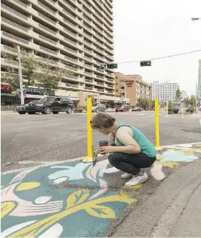  ?? IAN KUCERAK ?? Jill Stanton paints along Jasper Avenue Saturday as part of a pilot project to make over the street and draw more people to the area..