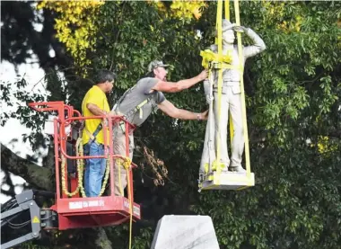  ??  ?? The Confederat­e statue located in the Circle at the University of Mississipp­i is lowered to the ground as part of the process to move it to the Confederat­e Soldiers Cemetery on campus, in Oxford, Miss. Tuesday, July 14, 2020. (Bruce Newman/the Oxford Eagle via AP)