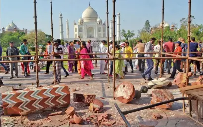  ?? AP ?? Tourists walk past debris after a powerful storm knocked down two minarets at the entry gates of the Taj Mahal in Agra. —