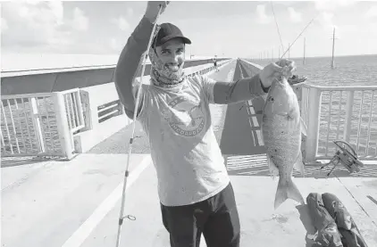  ?? PHOTOS BY KEVIN SPEAR/ORLANDO SENTINEL ?? Roger Calvo with a mutton snapper he caught from a Keys bridge.