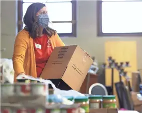  ?? JOE RONDONE/THE COMMERCIAL APPEAL ?? Manager of Volunteer Engagement Mandy Lamey prepares food boxes inside St. Anne Church that are given away Monday through Thursday every week for low-income families in need.