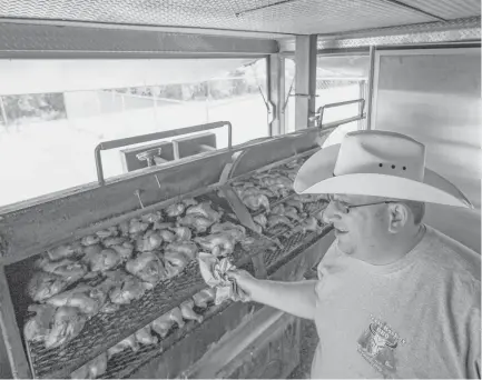  ?? Mark Mulligan / Houston Chronicle ?? Chaim Goldfeder checks on the chickens smoking in his kosher food trailer, Texas Kosher BBQ, which is serving community members and volunteers outside the Beren Academy in the Willowbend area.