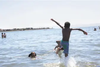  ??  ?? Kaden Jones sprints into the water to play with his siblings Kailee and Rylee Jones to escape the heat at Alameda Beach. Many in the Bay Area looked to coastal areas for relief from the heat.