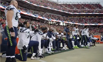  ??  ?? Seattle Seahawks players sit and kneel during the playing of the national anthem on Sunday. Photograph: Don Feria/AP