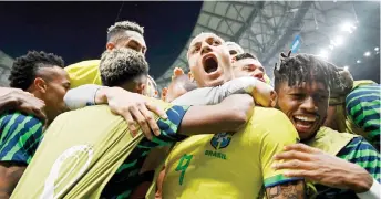  ?? — AFP photo ?? Richarliso­n (centre) celebrates with teammates after scoring Brazil’s first goal during the Qatar 2022 World Cup Group G football match against Serbia at Lusail Stadium.
