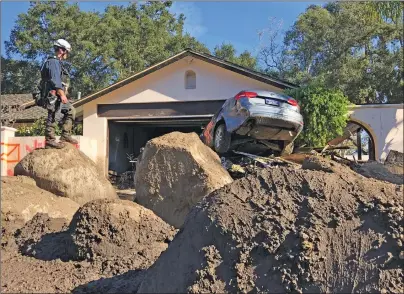  ?? MIKE ELIASON/SANTA BARBARA COUNTY FIRE DEPARTMENT VIA AP ?? In this Saturday photo provided by the Santa Barbara County Fire Department, Capt. John Pepper, Fresno Fire Department, and Rescue Squad Leader RTF-5 searches homes off East Valley Road in Montecito, Calif.