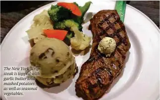  ??  ?? The New York Strip steak is topped with garlic butter and mashed potatoes as well as seasonal vegetables.