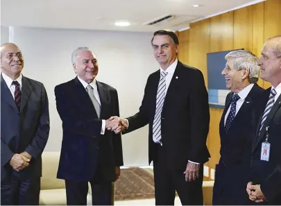 ??  ?? Bolsonaro e Temer ao lado dos futuros ministros Onyx Lorenzoni e Augusto Heleno (ambos à direita)