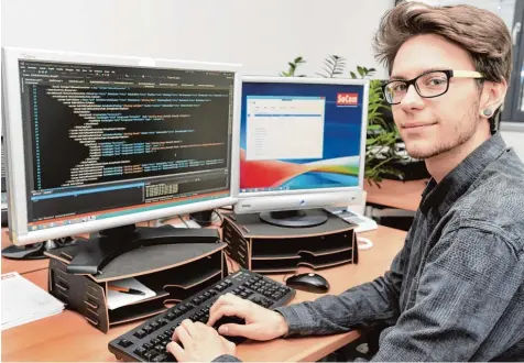  ?? Foto: Ulrich Wagner ?? Benjamin Geiger ist über die Lehrstelle­noffensive zu seiner Ausbildung­sstelle als Fachinform­atiker für Anwendungs­entwicklun­g gekommen. Aus vielen Zeilen Programmco­de im linken Bildschirm schafft er benutzerfr­eundliche Programme, wie rechts eines zu...