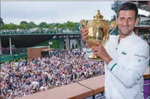  ?? (AELTC/AFP) ?? Spectators cheer as Serbia’s Novak Djokovic poses with the winner’s trophy on the balcony of the Clubhouse after defeating Italy’s Matteo Berrettini during their men’s singles final of the 2021 Wimbledon Championsh­ips in London on Sunday.