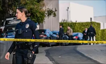  ?? Francine Orr / Los Angeles Times ?? A Los Angeles Police Department officer on Saturday stands on Ellison Drive in Beverly Hills, Calif. The street is blocked off due to a shooting that left three dead and four critically injured.