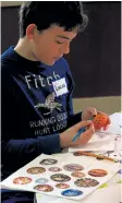  ?? PHOTOS BY KARENA WALTER /POSTMEDIA NETWORK ?? Above: Lucas Pijl, 11, of Jordan, uses wax to draw a design during a workshop for Ukrainian Easter eggs at St. George's parish hall in St. Catharines.
Above right: Finished Ukrainian Easter eggs provide inspiratio­n for workshop participan­ts learning...