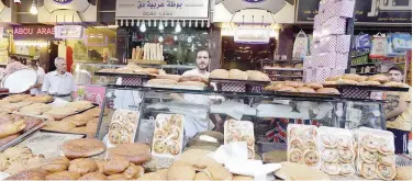  ?? Agence France-presse ?? ↑
A Syrian man displays bread and traditiona­l sweets for sale in Damascus recently.