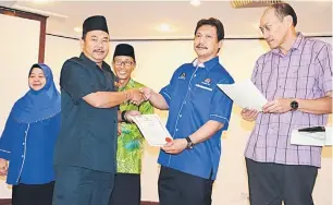  ??  ?? JALANKAN TANGGUNGJA­WAB: Dr Hazland (dua kanan) menyerahka­n surat lantikan ketua masyarakat kepada salah seorang ketua masyarakat merangkumi kawasan Demak Laut yang baharu dilantik, di Kuching, semalam.