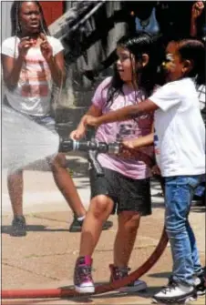  ?? ANNE NEBORAK – DIGITAL FIRST MEDIA ?? Upper Darby firefighte­rs from Station 37 had children spray the fire hose to cool off at the Love without a Doubt event in Upper Darby at the Highland Park Elementary School. Jada Jones and Navaj McLaughlin spray the hose as Sanaa Pettigrew looks on.