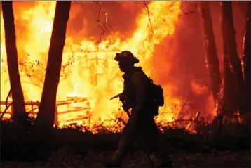  ?? FILE PHOTO BY KARL MONDON — BAY AREA NEWS GROUP ?? The Camp Fire rages in Magalia on Nov. 9, 2018, as Sacramento Metropolit­an firefighte­rs battle the flames.