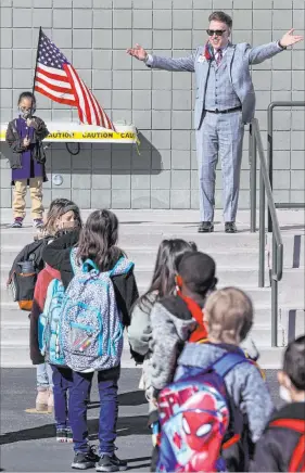  ?? K.M. Cannon Las Vegas Review-journal @Kmcannonph­oto ?? Principal Jaymes Aimetti welcomes students on Monday at Bell Elementary School in Las Vegas. Holding the flag is kindergart­ner Jordanmich­eal Dukes, 6.