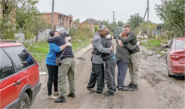  ?? Reuters ?? ±
Neighbours embrace each others after they return from evacuation to the liberated village of Kamianka, in Kharkiv region, on Monday.