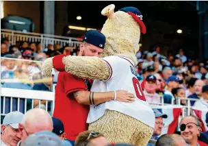  ?? PHOTOS BY CURTIS COMPTON / CCOMPTON@AJC.COM ?? Braves mascot Blooper hugs a fan at SunTrust Park after the Braves allowed 10 runs in the first inning against the Cardinals in Game 5 of the National League Division Series. It never got much better as the Braves were ousted from the playoffs.