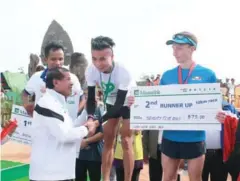  ?? SARETH MEAS ?? Tourism Minister Thong Khon congratula­tes Qi Bian, the winner of the men’s 21km run.